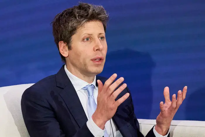 Sam Altman berbicara sambil mengangkat tangan.